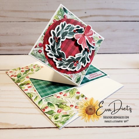 Photo of the front view of the Diamond Pop-Up Fun Fold Card that is in red and green colors with a holiday wreath on the front sitting on a matching color coordinated envelope.