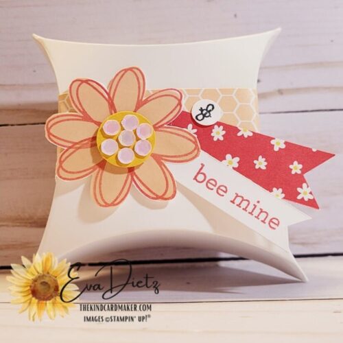 Square Pillow Treat Box in white, decorated with a belly band of pink honeycomb pattern, two small flags, one of which says bee mine, and topped off with am 8 petal pink flower with a yellow center covered in white sequins designed by Eva Dietz, The Kind Card Maker.